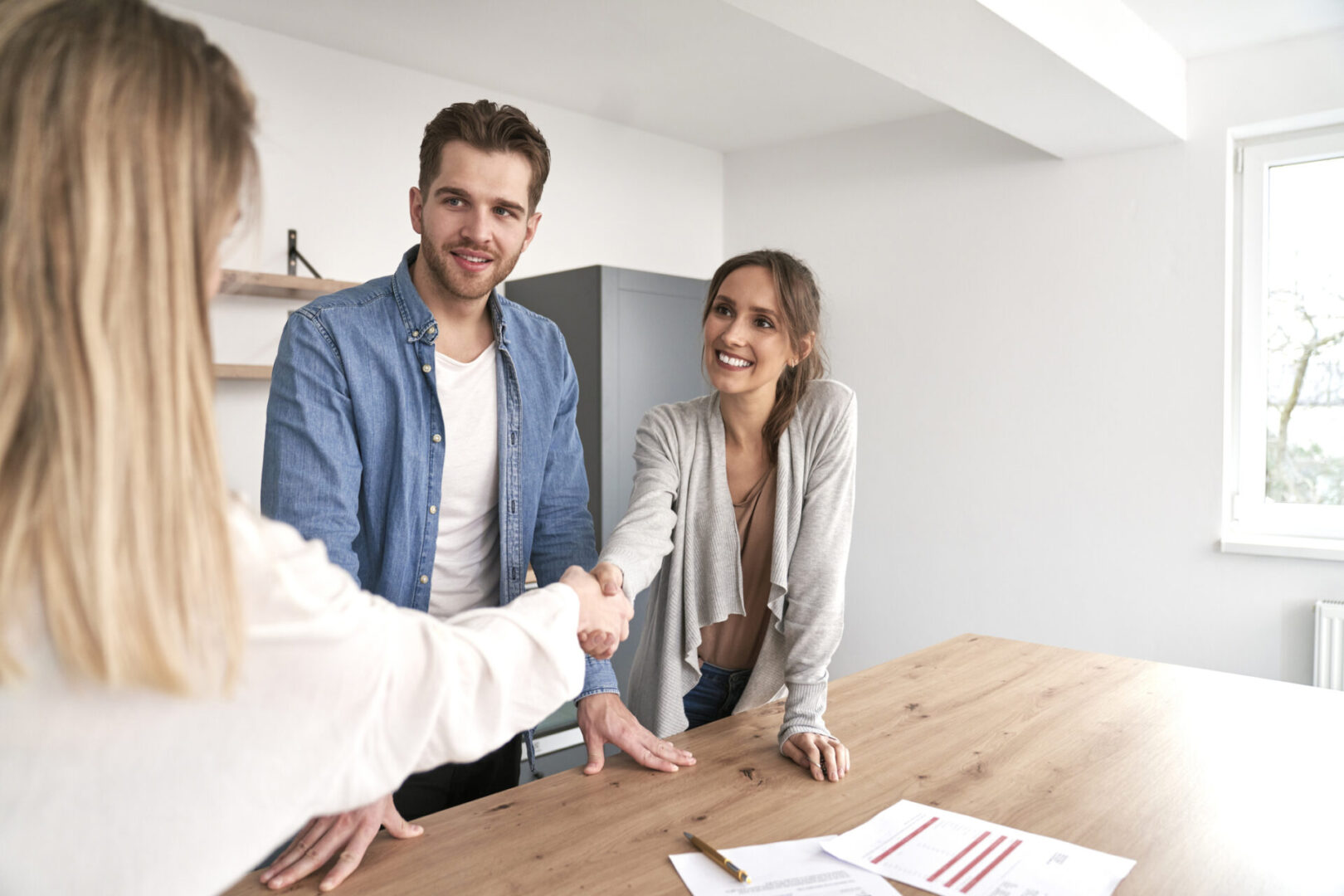 Handshake of real estate agent and young caucasian couple
