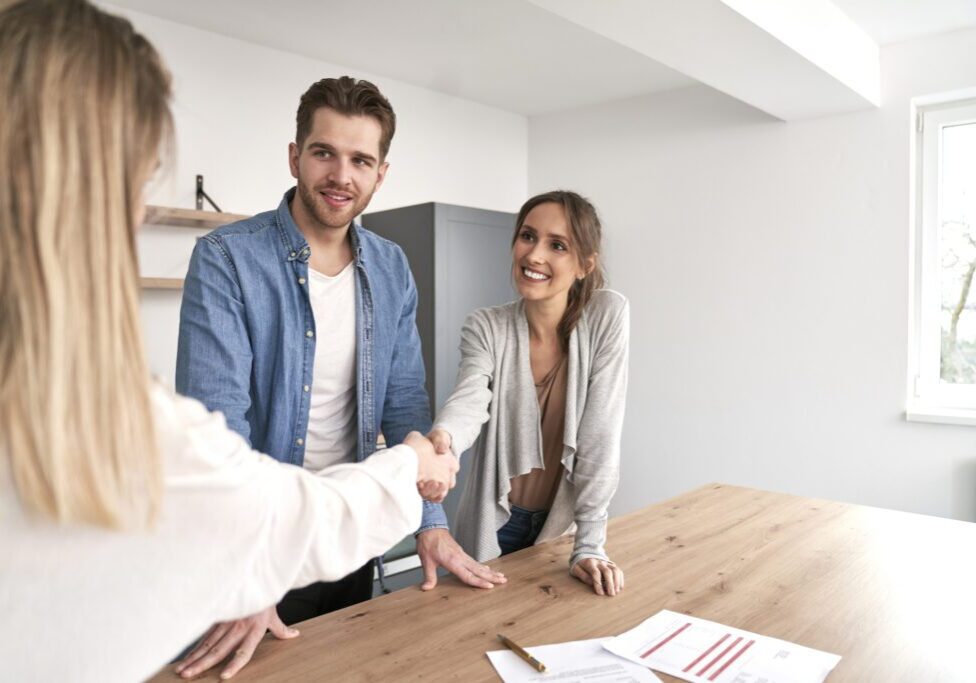 Handshake of real estate agent and young caucasian couple